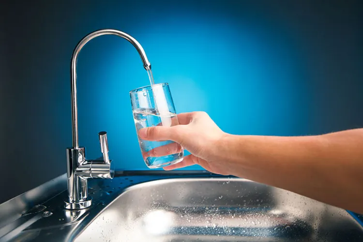 Vaso llenándose con agua tratada desde una canilla de purificador