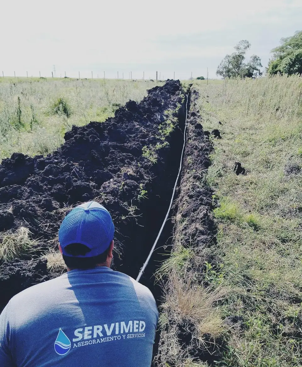 Técnico de SERVIMED colocando la cañería de riego dentro de una zanja en el campo