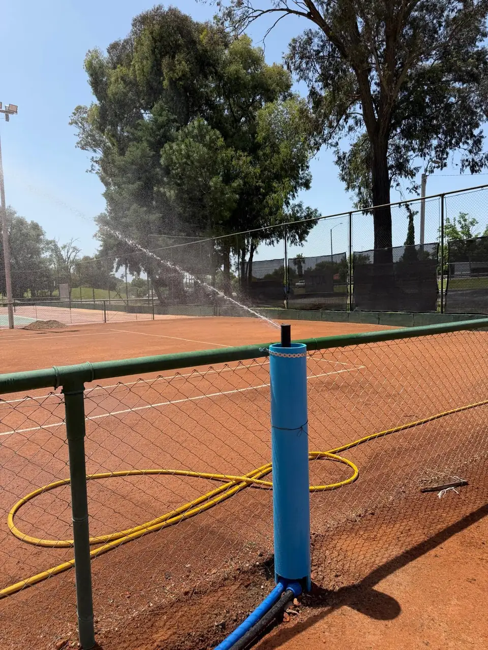 Aspersor de riego funcionando en una cancha de tenis de polvo de ladrillo, instalación de SERVIMED