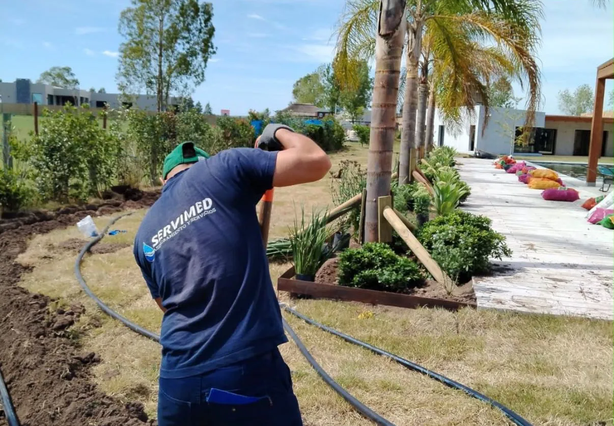Técnico de SERVIMED tendiendo las mangueras de riego en el jardín de una casa